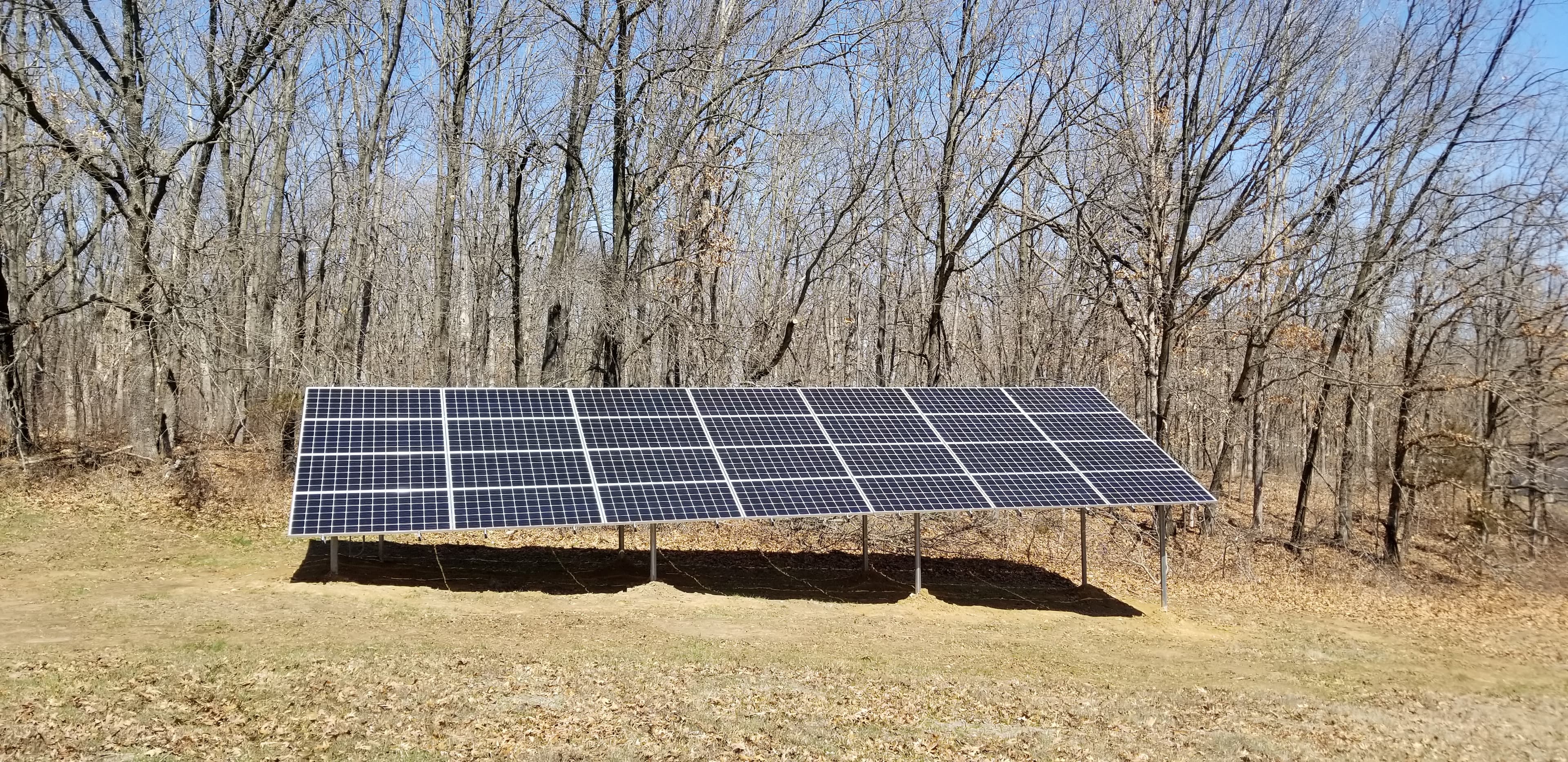 Ground-mounted solar array in a wooded clearing